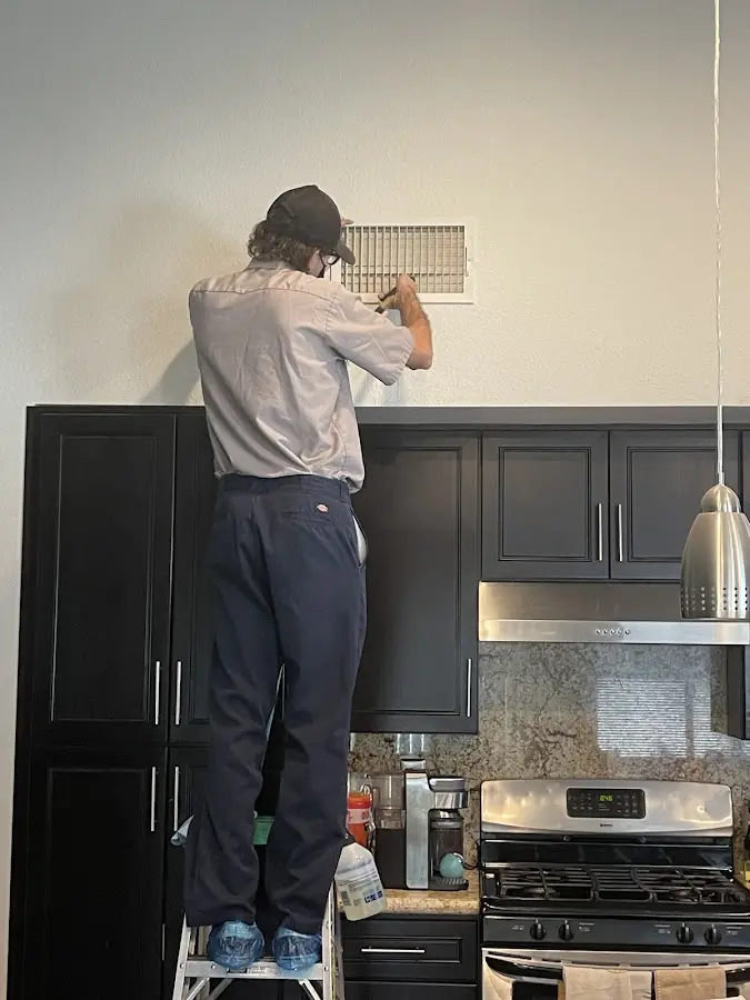 Technician inspecting an air vent during HVAC service in Laconia